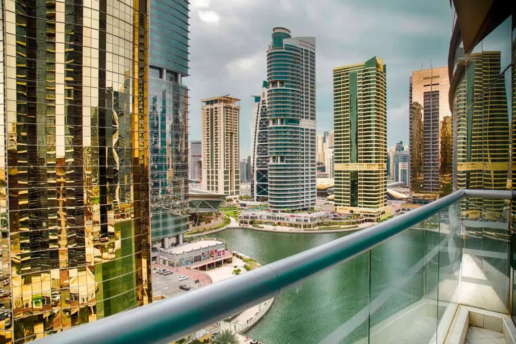 View from a luxury apartment balcony overlooking Dubai Marina canal and skyline.
